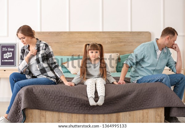 Sad family sitting on\
bed after quarrel