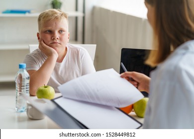 Sad fat child listening to nutritionist's recommendations. Water and green apple. Diet and weight loss. - Powered by Shutterstock