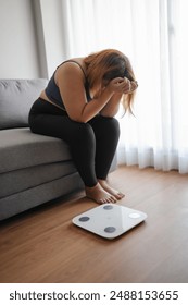 Sad fat woman with fat upset bored of dieting Weight loss fail  Fat diet and scale sad Obese asian female on weight scale at home weight control.