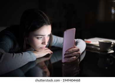 Sad Female Checking Smart Phone Content In The Dark Night At Home