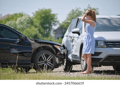 Sad female driver speaking on sellphone on street side calling for emergency service after car accident. Road safety and insurance concept