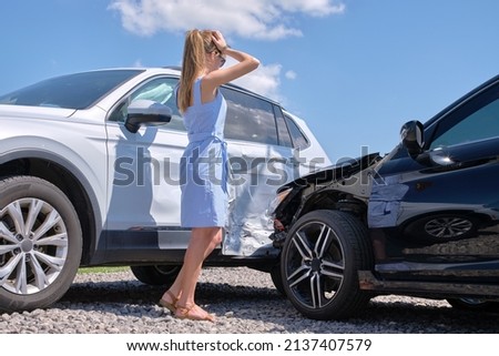 Sad female driver standing on street side shocked after car accident. Road safety and vehicle insurance concept