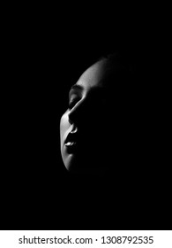 sad female face with closed eyes on dark with back light, monochrome