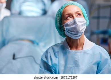 Sad Female Surgeon Looking Up After Operation, In Contemplation, She Is Thoughtful. In Medical Uniform