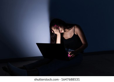 Sad And Female Teenager With Tablet Computer And Laptop Suffering Cyberbullying And Harassment Being Online Abused By Stalker Or Gossip Feeling Desperate And Humiliated In Cyber Bullying.