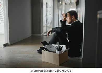 Sad Fired. Let Go Office Worker Packs His Belongings into Cardboard Box and Leaves Office. Workforce Reduction, Downsizing, Reorganization, Restructuring, Outsourcing. Mass Unemployment Market Crisis.
