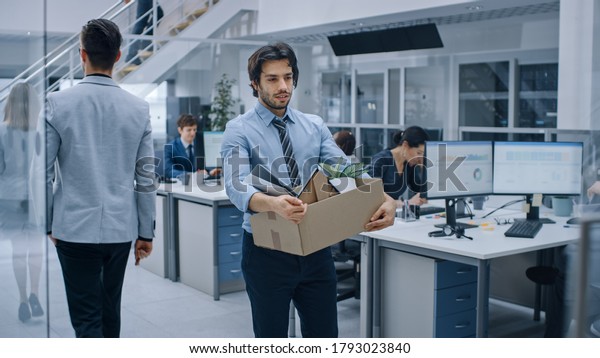 Sad Fired / Let Go Office Worker Packs His\
Belongings into Cardboard Box and Leaves Office. Workforce\
Reduction, Downsizing, Reorganization, Restructuring, Outsourcing.\
Shot with Dark Ambient