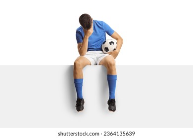 Sad football player sitting on a blank panel isolated on white background - Powered by Shutterstock