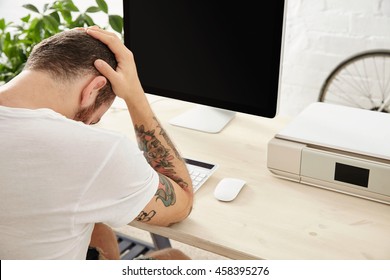 Sad Freelancer Has A Hard Project And Holds His Head In Hands While Sitting In Front Of His Working Computer Screen Side View