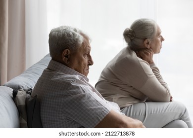 Sad Frustrated Old Couple Going Through Conflict, Row, Quarrel, Ignoring Each Other, Sitting On Couch At Home. Upset Senior Elder Husband And Wife Thinking Over Family, Financial Problems