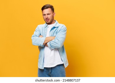 Sad Frustrated Tanned Handsome Man In Blue Basic T-shirt Think About Problem At Work Fold Arms Posing Isolated On Yellow Studio Background. Copy Space Banner Mockup. People Emotions Lifestyle Concept