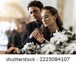 Sad, funeral and flowers with couple and coffin in church for death, respect and mourning. Grief, goodbye and empathy with man and woman loss at casket with depression, remember and farewell memorial