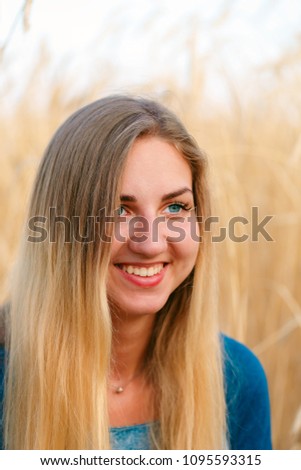 Sad girl closeup in wheat . Young girl is in a wheat field, on a background of ripe ears, in a blue dress