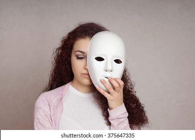sad girl hiding face behind mask