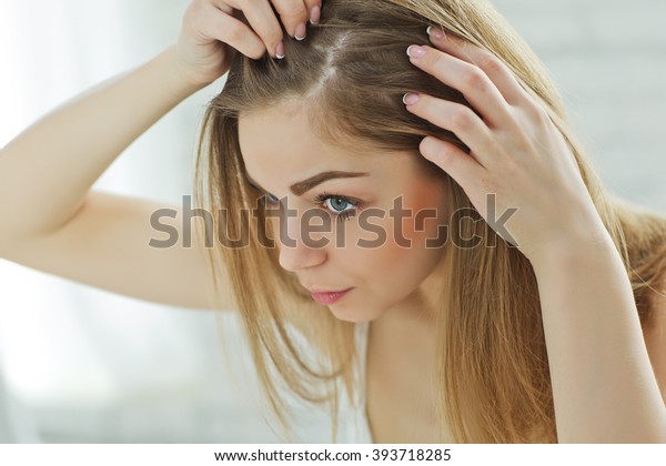 Sad girl looking at her\
damaged hair