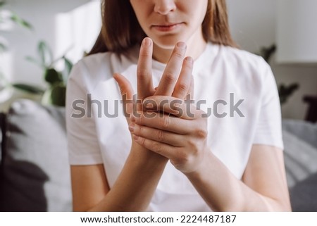 Sad girl massage hand with wrist pain, rheumatoid arthritis concept. Close up of young woman suffer from numbing pain in hand, numbness fingertip, arthritis inflammation, peripheral neuropathies