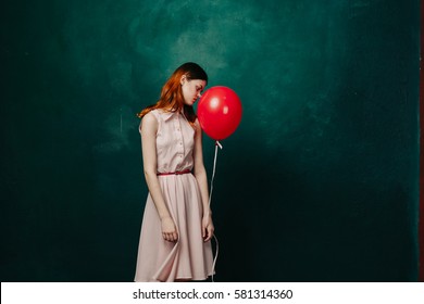 The Sad Girl With A Red Balloon On A Green Background In A Dress