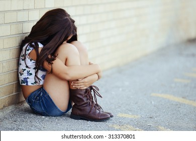 sad girl siting by brick wall