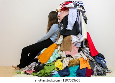 Sad Girl Sitting Near A Big Pile Of Differect Clothes