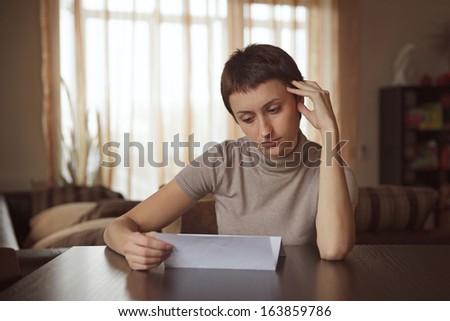 Sad girl sitting and reading a letter