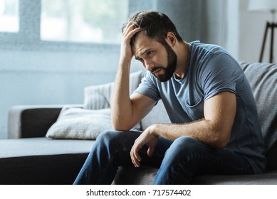 Sad gloomy man holding his forehead - Shutterstock ID 717574402