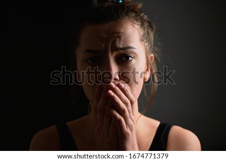 Sad grieve miserable desperate crying woman with tears eyes and folded hands on a dark black background during trouble, life difficulties, loss and emotional problems