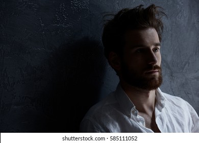 Sad, Handsome Man Standing Against Dark Wall