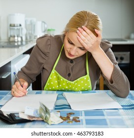 Sad Housewife Filling In Utility Payments Bills At  Home