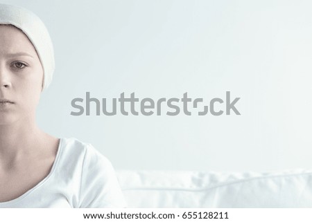 Sad ill woman wearing headkerchief in white room