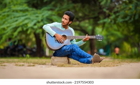 A Sad Indian Boy Playing Guitar