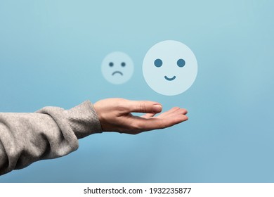 A sad and joyful face in the hand of a man. Choosing between the negative and the positive in a person's life - Shutterstock ID 1932235877