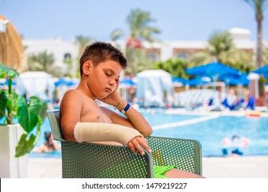 Sad Kid With Arm Cast Neer Swimming Pool, Child With Broken Arm Can't Enjoy His Holiday. Kid Not Able To Swim In Water With Arm Cast