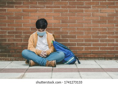 Sad Kid With Medical Mask And Backpack Sitting On The Ground