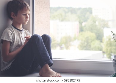 Sad Kid Sitting On Window Shield And Looking Out The Window