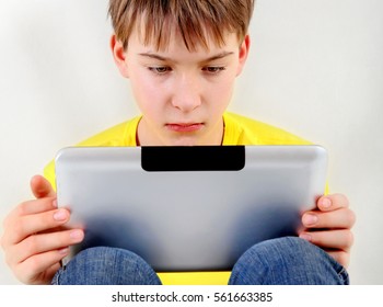 Sad Kid With Tablet Computer On The White Wall Background