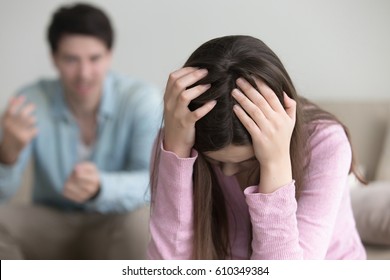 Sad lady holding hands on head thinking of divorce, unhappy couple arguing, upset woman tired of constant conflicts, addicted partner, bad relationships, frustrated girl ignoring boyfriend in anger 