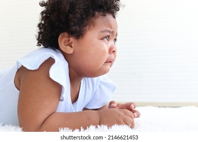 Sad little African American girl with curly hair crying, drop of tear running down cheek, eye discharge, kid getting upset and bad-tempered.