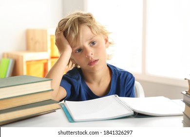 Sad Little Boy Doing Homework At Table Indoors