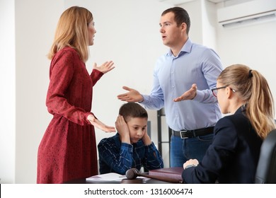 Sad little boy with his quarreling parents in lawyer's office. Concept of child support