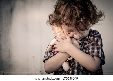 sad little boy hugging a doll
