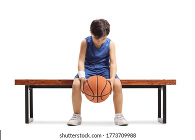 Sad little boy sitting on a bench with a basketball isoalted on white background - Powered by Shutterstock