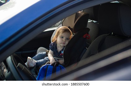 Sad Little Child Girl Alone In The Car Waiting For The Parent Strapped In A Child Car Seat. It Is Dangerous To Leave Children In The Car In Hot Weather