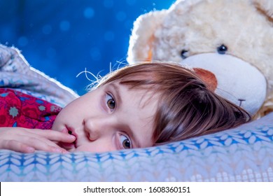 Sad Little Child Girl Sleeping On Bed Against Starry Sky As A Symbol Of Loneliness And Pain. Children's Fear And Anxiety.