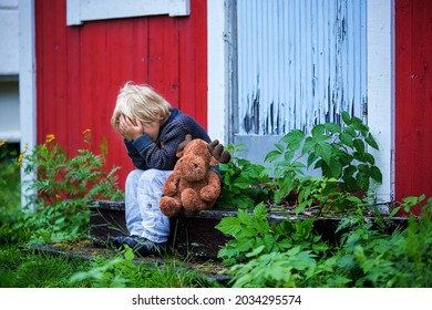 Sad Little Child, Preschool Boy, Holding Stuffed Raindeer Toy, Sitting On Stairs In Front Of Old Ruined House, Sad And Crying