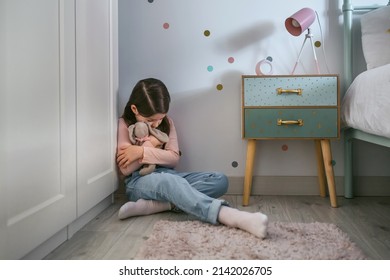 Sad Little Girl Hugging Her Stuffed Toy Sitting On The Floor In Her Bedroom