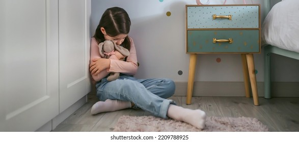 Sad Little Girl Hugging Her Stuffed Toy Sitting On The Floor In Her Bedroom