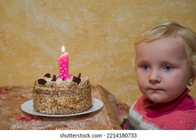 Sad Little Girl On Her Birthday,a Little Girl Sits At The Table With A Cake And Is Sad