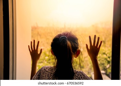 Sad Little Girl In Room And Looking Out The Window