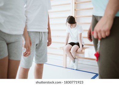 Sad little girl sitting alone on a bench during physical education classes at school - Shutterstock ID 1830771923