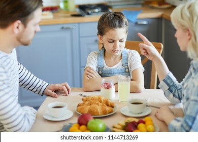 Sad little girl sitting by table while mother forbidding her to have dessert because of bad behavior - Shutterstock ID 1144713269